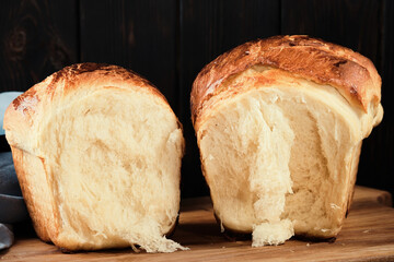 Fresh homemade organic brioche bun on rustic table top view. Buns broken in half. Traditional French brioche, baked concept. Close-up, selective focus