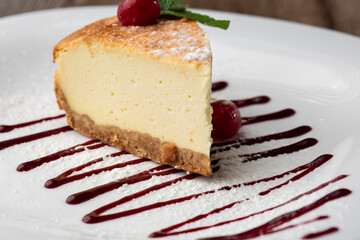 Cheesecake New York or classic cheesecake with caramel. Closeup view. Tasty breakfast. Piece of cake on white plate, on wooden background.