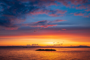 Obraz premium A setting sun makes for beautiful island silhouettes in the foreground and colorful skies above