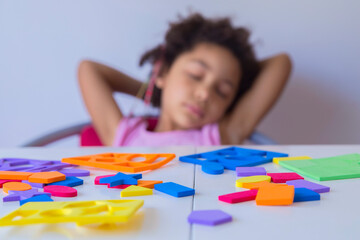Cute mixed race girl boring from of playing with educational toys and sleeping on chair. Preschool learning concept.