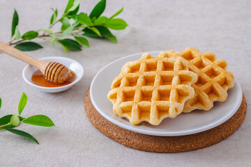 Waffles on white plate and honey in bowl