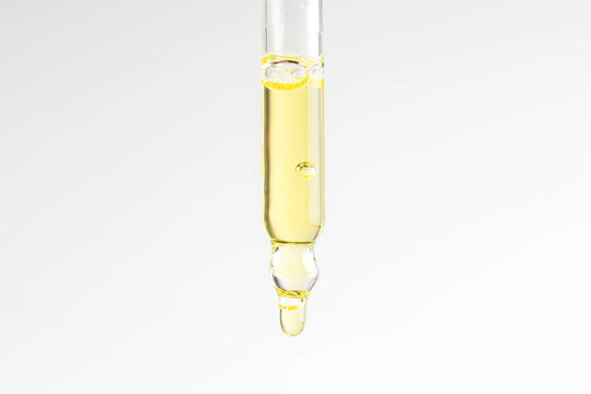 Cosmetic pipette with vitamin C serum or essential oil on light background. Skin care anti-aging treatment.