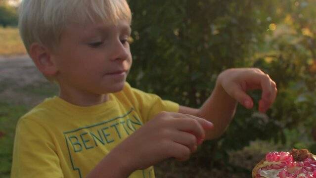 Mom invites children to taste the freshly picked juicy fruit. Ripe red pomegranate in hands at sunset. The salivating red grains glisten in the sun. Kids are happy to eat. IT, Borgagne, 6.10.2021 