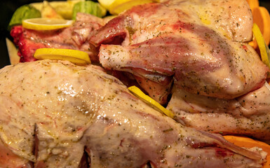Lamb leg with bone uncooked with potato and herb in oven pan. Close up view.