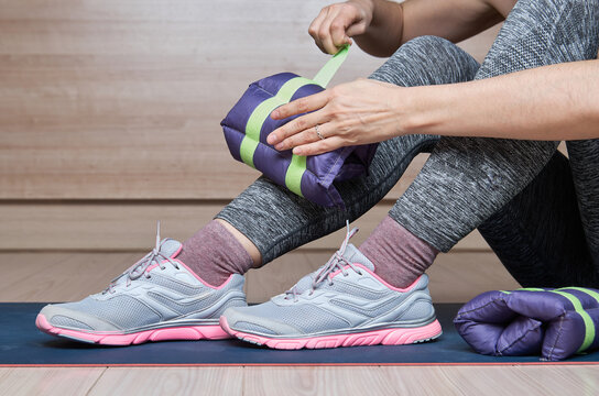 Woman At Gym Putting Ankle Weights