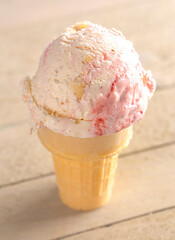 Strawberry Cheesecake Ice Cream in a Cone on a Picnic Table