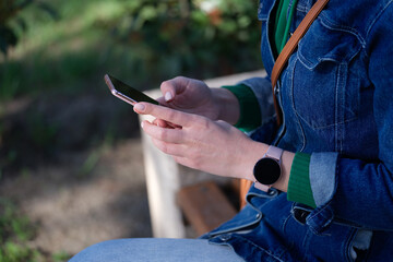 Woman sitting on bench is holding smartphone