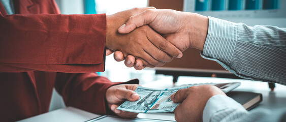 Shaking hands with congratulations on an evil plan, Businessmen give dollars to bribe employees in signing contracts to buy illegal land and real estate, corruption and Bribery concept.