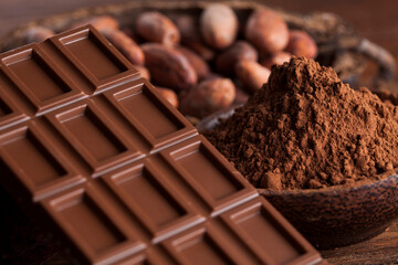 Chocolate bar, candy sweet, cacao beans and powder on wooden background