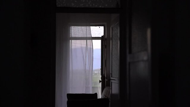 Through the open balcony door you can see outside and the wind moves the curtain