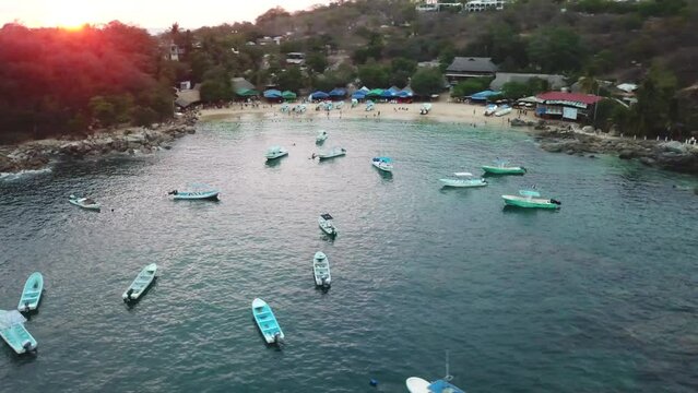 Tourism and fisher boats in  Angelito Port in Oaxaca Mexico during sunset 