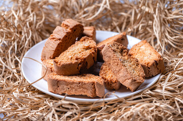 crispy rusks or toast on a white plate, straw background, closeup