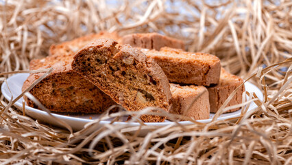 crispy rusks or toast on a white plate, straw background, closeup