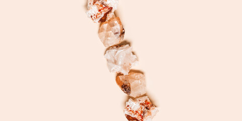 White beige quartz crystals on pale pink color background with copy space,  top view natural...