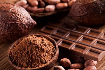 Chocolate bar, candy sweet, cacao beans and powder on wooden background