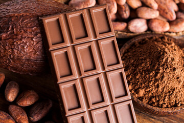 Chocolate bar, candy sweet, cacao beans and powder on wooden background