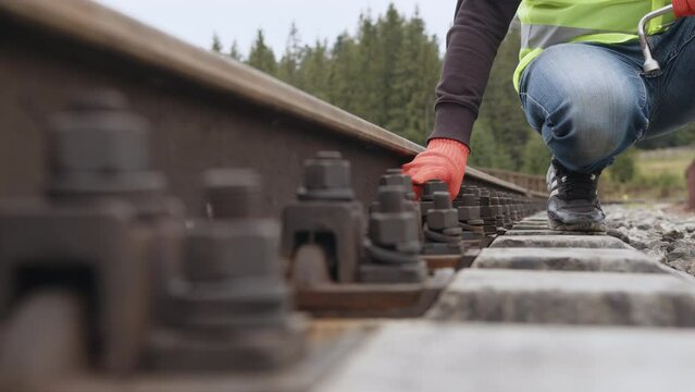 Work on railway. Worker tightens the screw on railroad. Engineer walking and check track work on railways. Inspection and control of railway tracks is carried out by the engineer