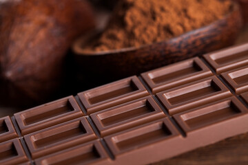 Chocolate bar, candy sweet, cacao beans and powder on wooden background