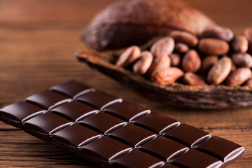 Dark homemade chocolate bars and cocoa pod on wooden