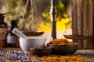 Herbs, berries and flowers with mortar, on wooden table background