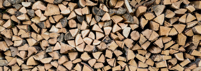 Background of stacked chopped wood logs. Pile of wood logs ready for winter. Wooden stumps,...