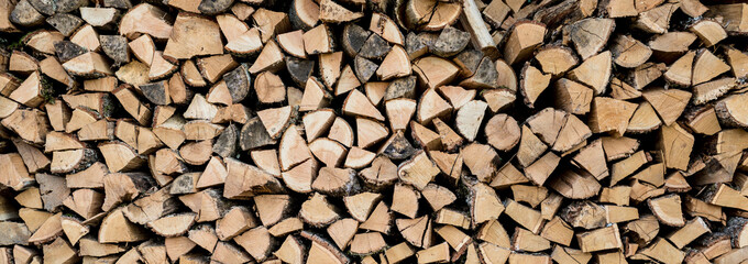 Background of stacked chopped wood logs. Pile of wood logs ready for winter. Wooden stumps, firewood stacked in heap