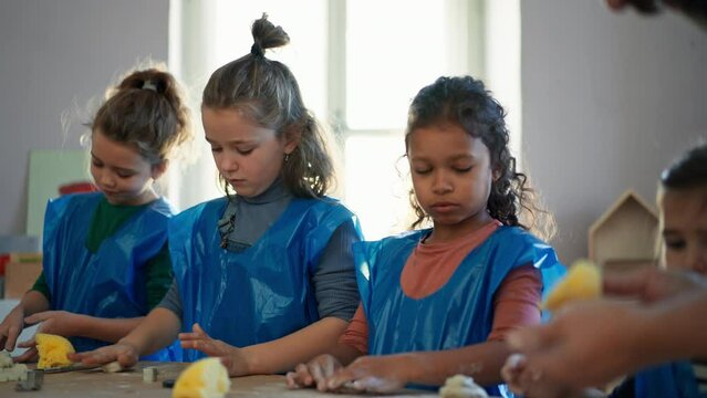 Group of little kids with teacher working with pottery clay during creative art and craft class at school.