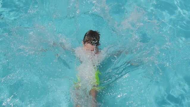 Caucasian Boy Falling Backwards Into Pristine Swimming Pool Water, Topdown View