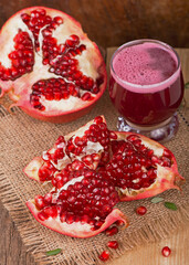 Juicy pomegranate and its half Beautiful composition with juicy pomegranates, on old wooden table