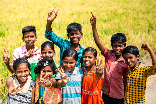 Group of village teenage kids standing with smiling by looking at camera near paddy field - concept of friendship, happiness and childhood lifestyle.