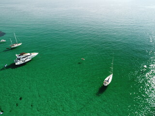 Aerial panoramic view of seascape with crystal clear azure sea and rocky shores. Yachts in a beautiful lagoon on backdrop of rocks. The concept of an ideal destination for summer travel and vacation.