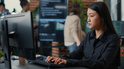 Programer writing algorithm focused on compiling source code sitting at desk in software...