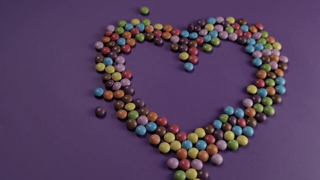 Colorful mixed candy heart. Valentine's Day Love.  The 14th of February. Сhocolate dragee drop. Purple pack shot background FullHD. Sweet packshot