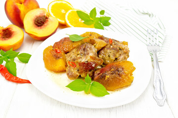 Turkey with peaches in plate on light wooden board