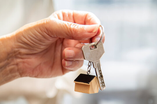 hand holding keychain with house or apartment keys
