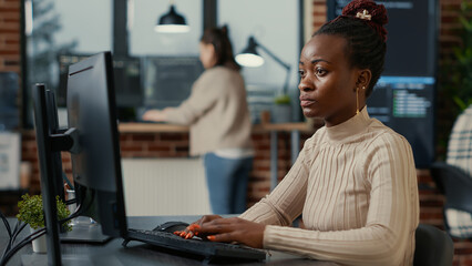 African american software engineer working focused looking at computer screen while typing in it...