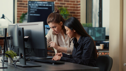 Team of coworkers comparing source codes running on laptop screen and computer monitor in it...