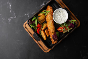 One piece of baked salmon grilled lemon and salt on a dark plate with potatoes. marble background