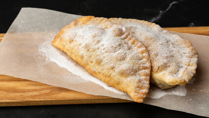 Uzbek eastern Tatar cuisine, sweet cheburek on a wooden board. Cheburek - fried pie with chocolate.