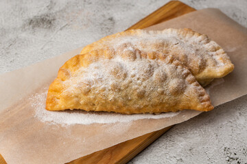 Uzbek eastern Tatar cuisine, sweet cheburek on a wooden board. Cheburek - fried pie with chocolate.