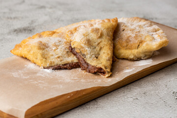 Uzbek eastern Tatar cuisine, sweet cheburek on a wooden board. Cheburek - fried pie with chocolate.