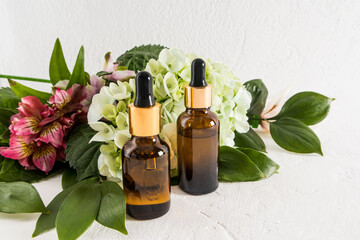 Front view of two glass bottles with a dark glass dropper with cosmetic skin care product. the concept of natural cosmetics. Flowers.