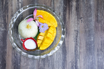 Sweet Barracuda Mango served on banana leaves with sticky rice and coconut milk decorated with tropical flower. Top View