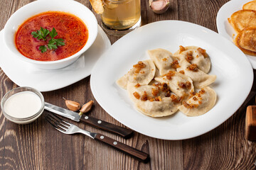 Traditional ukrainian dish vareniki and borscht served with greaves and sour cream. Close up view of traditional Ukrainian food.