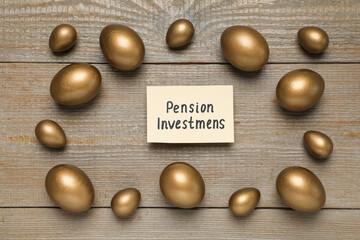 Golden eggs and card with phrase Pension Investments on wooden table, flat lay