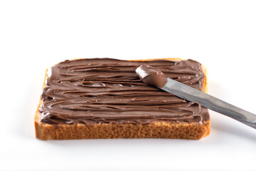 Toast bread spread with chocolate hazelnut spread with a knife on a white background.