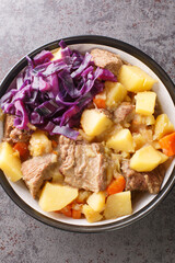 English Scouse is a beef or lamb stew with vegetable closeup in the plate on the table. Vertical top view from above