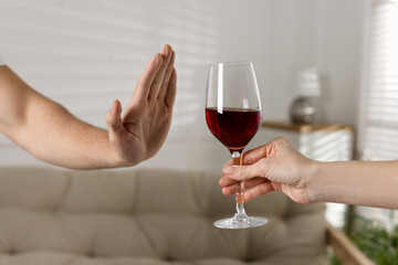 Man refusing to drink red wine indoors, closeup. Alcohol addiction