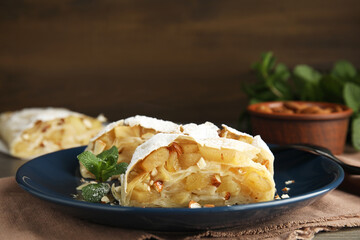 Delicious apple strudel with almonds, powdered sugar and mint on table, closeup. Space for text