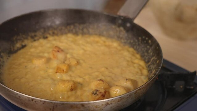 Delicious creamy coconut curry seafood scallops simmering on shallow frying pan with aromatic smell, close up shot professional chef cooking concept.
